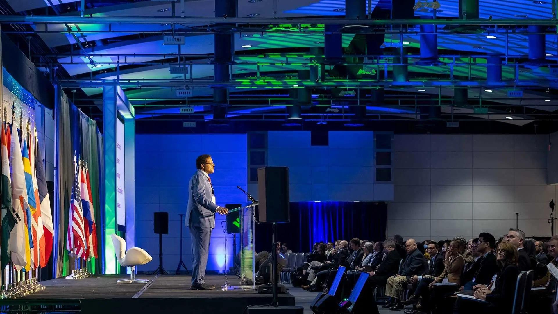 President Pines speaking to Quantum World Congress in front of flags